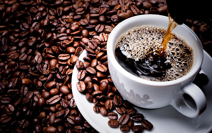 Mug on plate filled with coffee surrounded by coffee beans